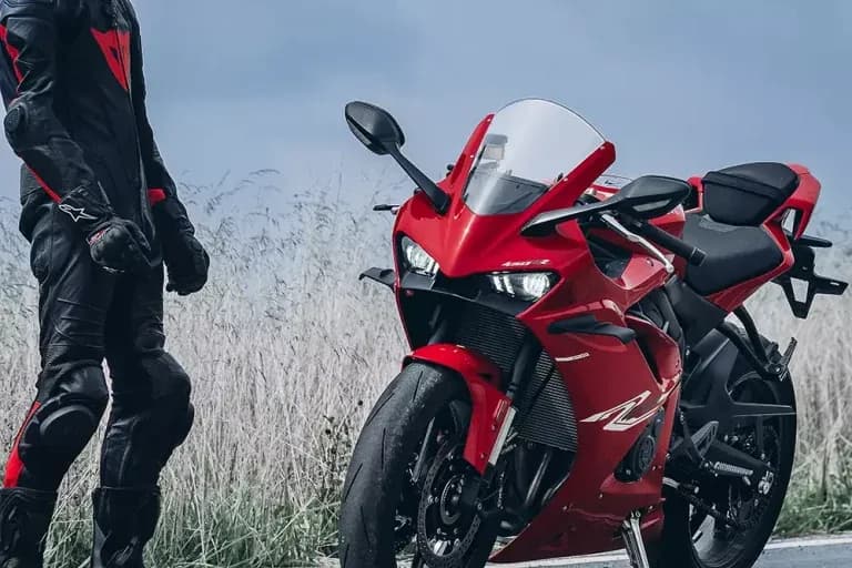 Motocicleta KOVE deportiva roja junto a un piloto de pie con traje de cuero negro y rojo; en el carenado delantero se lee «450 R»