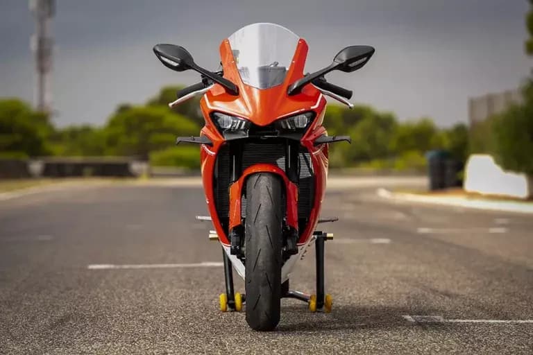 Motocicleta KOVE deportiva roja vista de frente sobre caballetes de taller en el asfalto de una vía cerrada