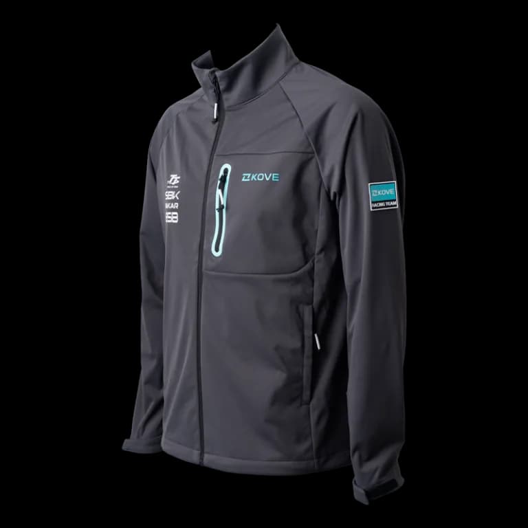 Chaqueta softshell gris oscuro con logotipo KOVE en verde agua, bolsillo pectoral con cremallera verde agua y parche «KOVE Racing Team» en la manga